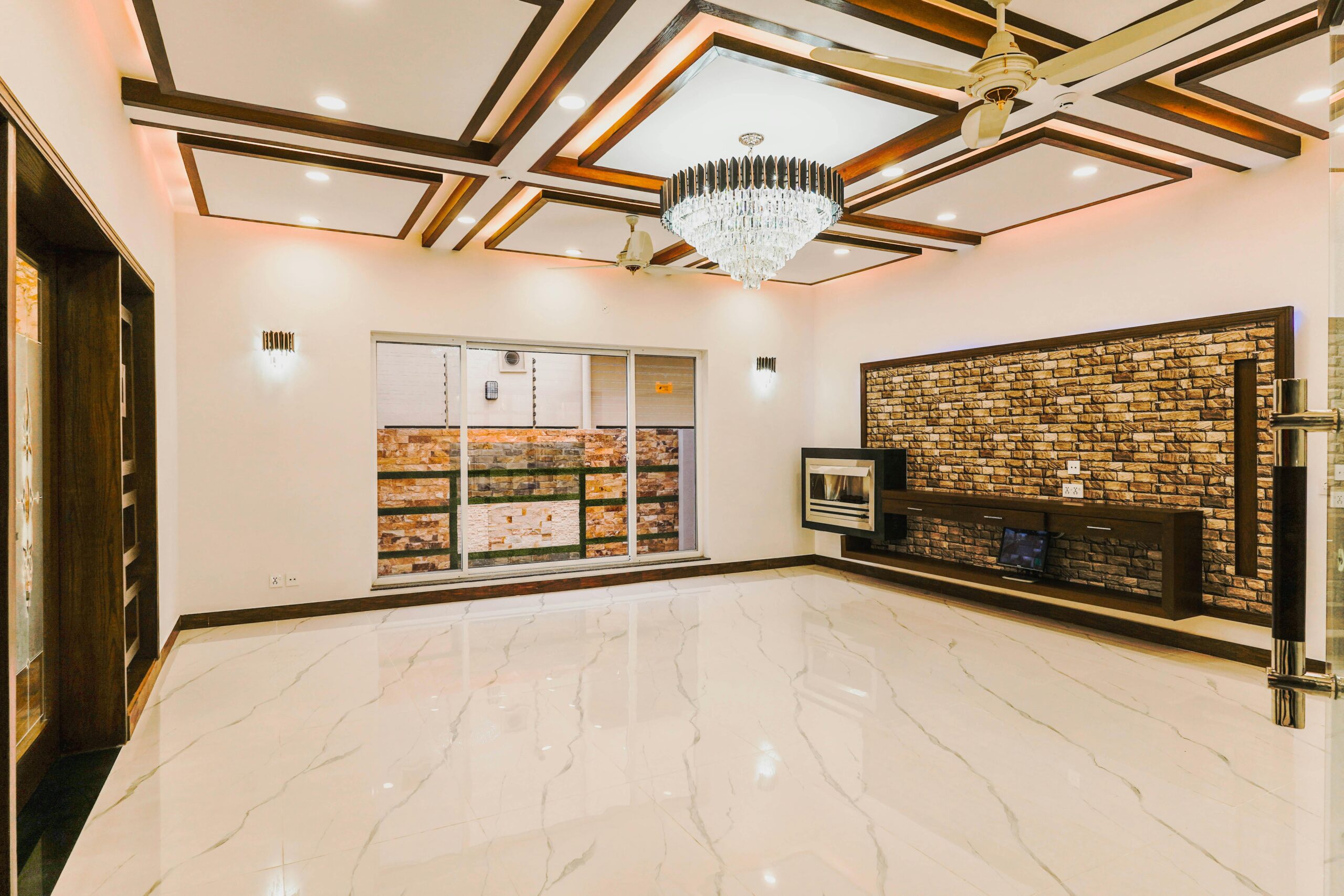 Elegant modern living room with a crystal chandelier and marble flooring.