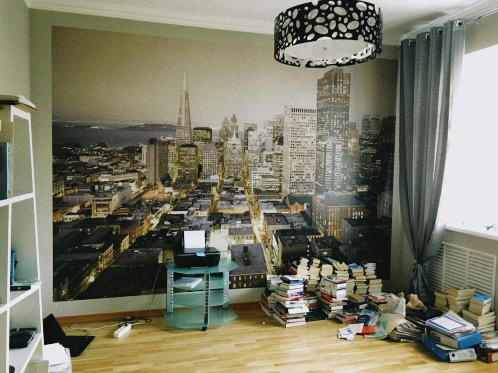 Room interior with a large San Francisco skyline wallpaper and stacks of books.